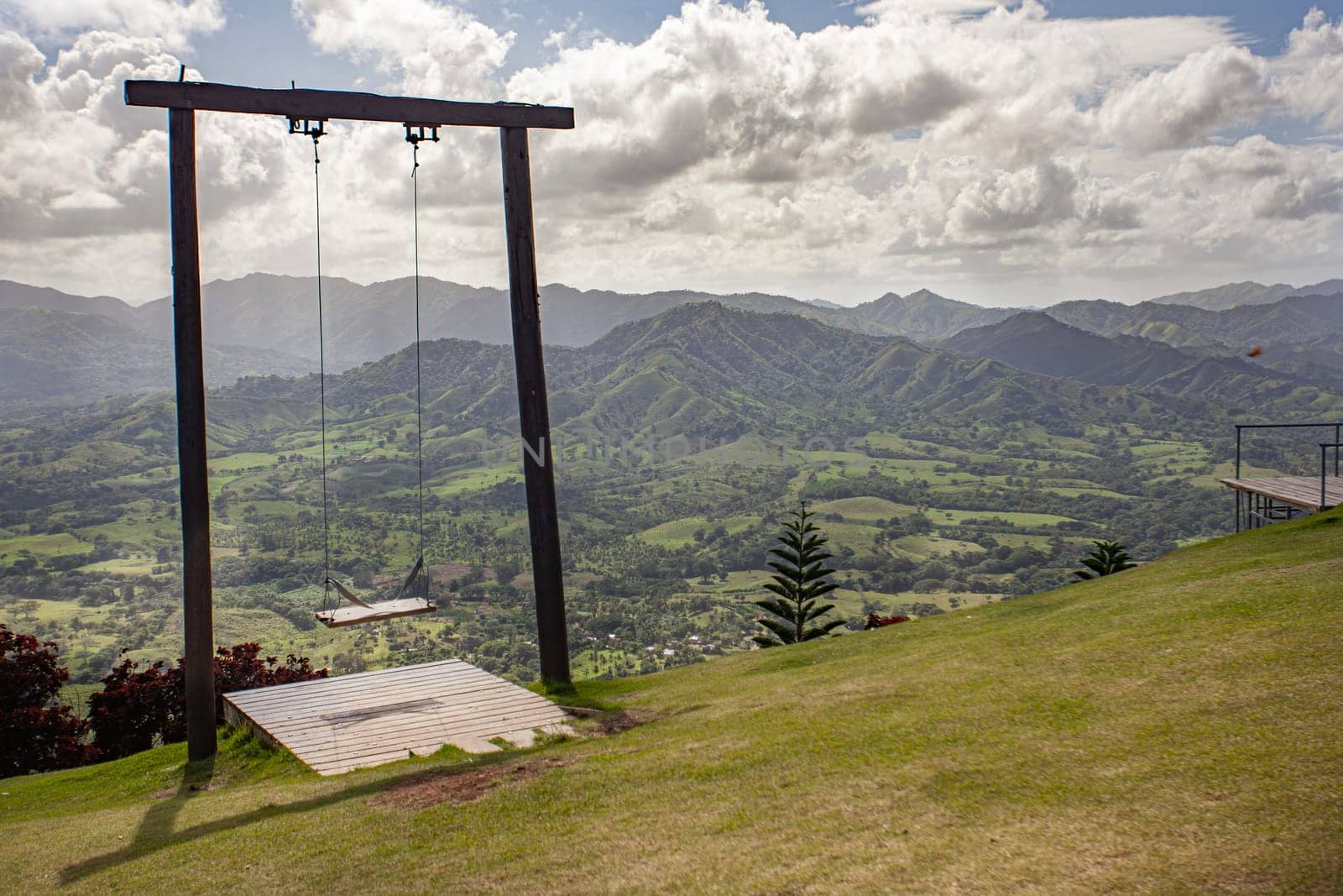 Wooden swing set atop montana redonda overlooking a vibrant green valley in the dominican republic