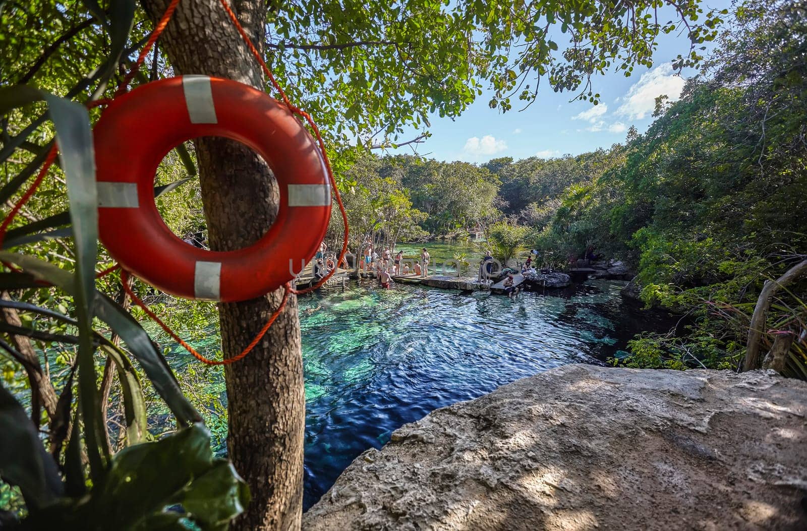 Tourists swimming and relaxing at the beautiful cenote azul in riviera maya, mexico, a popular destination for its crystal-clear waters