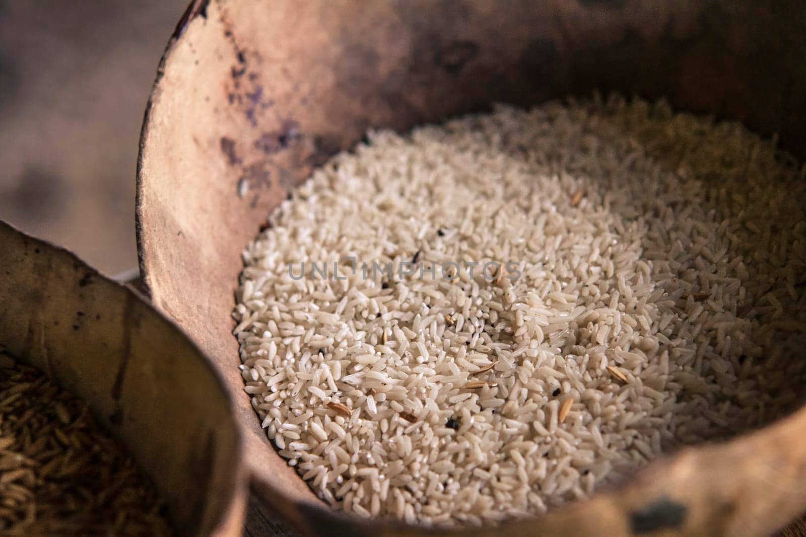 Close-up of uncooked rice in a weathered wooden bowl, showcasing the staple food's natural state