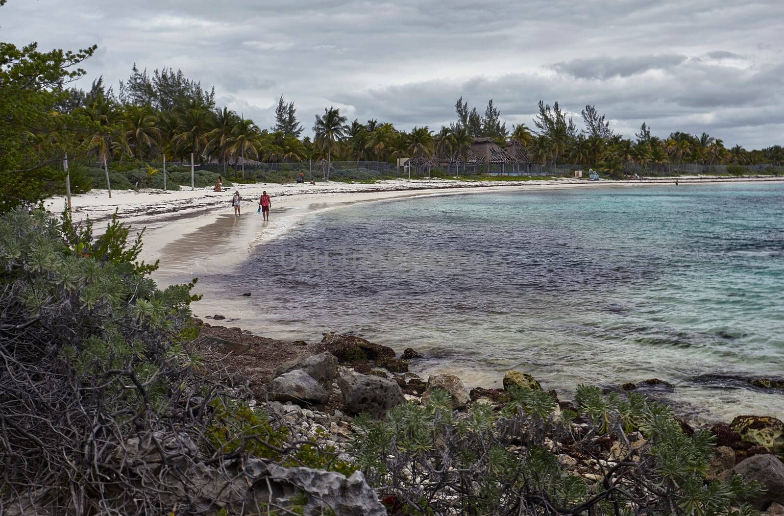 Tourists walking on the beautiful xpu-ha beach in riviera maya, mexico, enjoying the cloudy sky