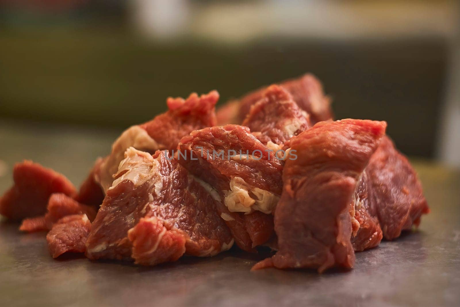 Freshly cut pieces of red meat are sitting on a metal table, ready for packaging or further processing by a butcher