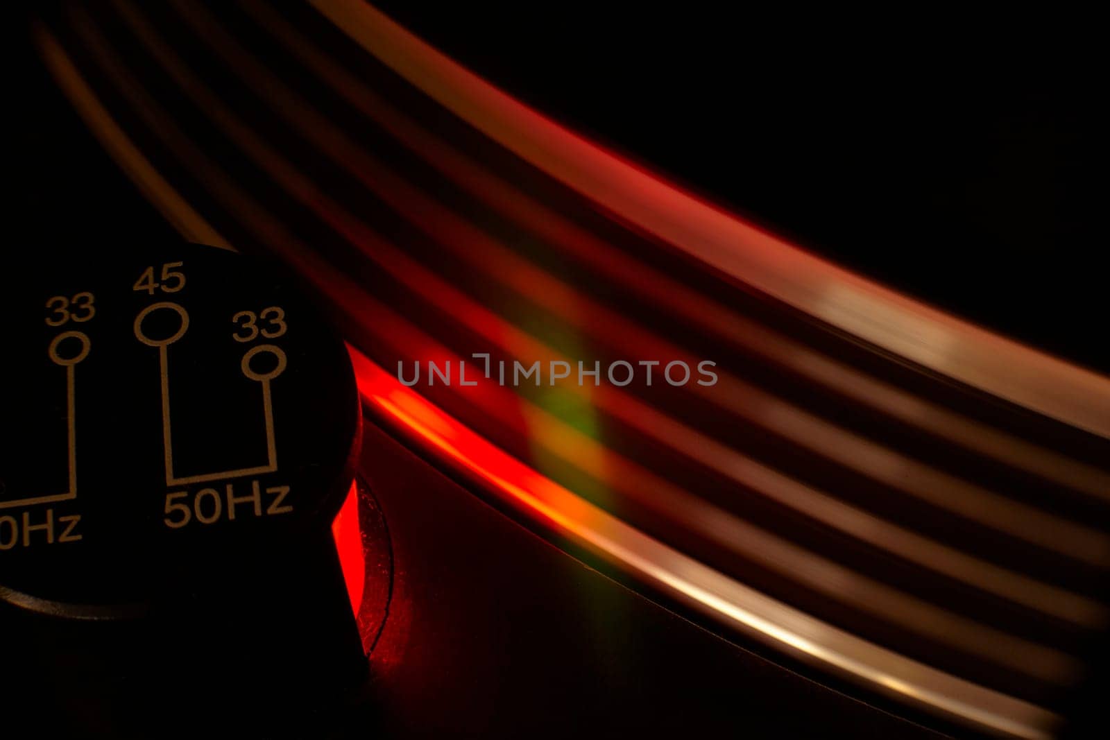 Close-up of a vintage turntable rotating with a red light effect, showcasing the speed selector switch
