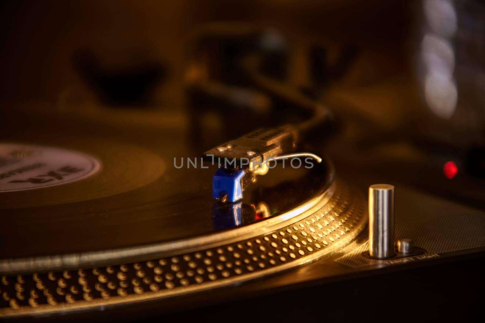Close-up of a turntable playing a vinyl record, the needle gently tracing the grooves of the spinning disc in a warm, dimly lit setting