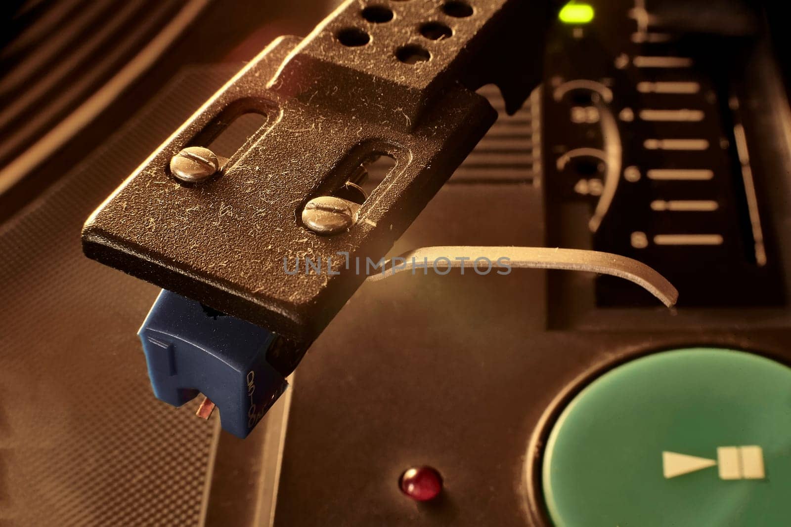 Close-up of a turntable's tonearm with a blue cartridge, playing a vinyl record, evoking nostalgia and the warm sound of analog music