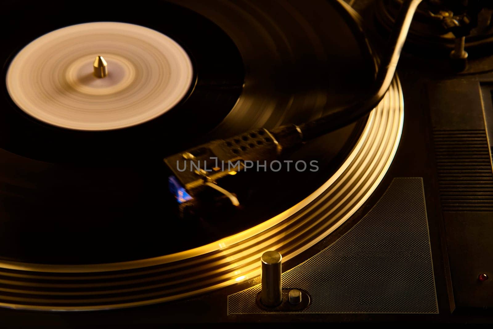 Close-up of a vinyl record spinning on a turntable, illuminated by warm light, representing music and entertainment