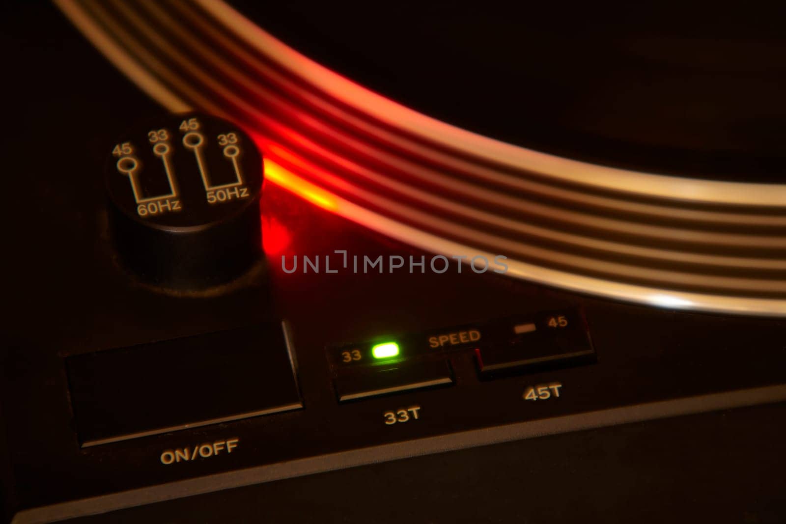 Close-up of a vintage turntable playing a vinyl record, illuminated by a red light, creating a warm and nostalgic atmosphere