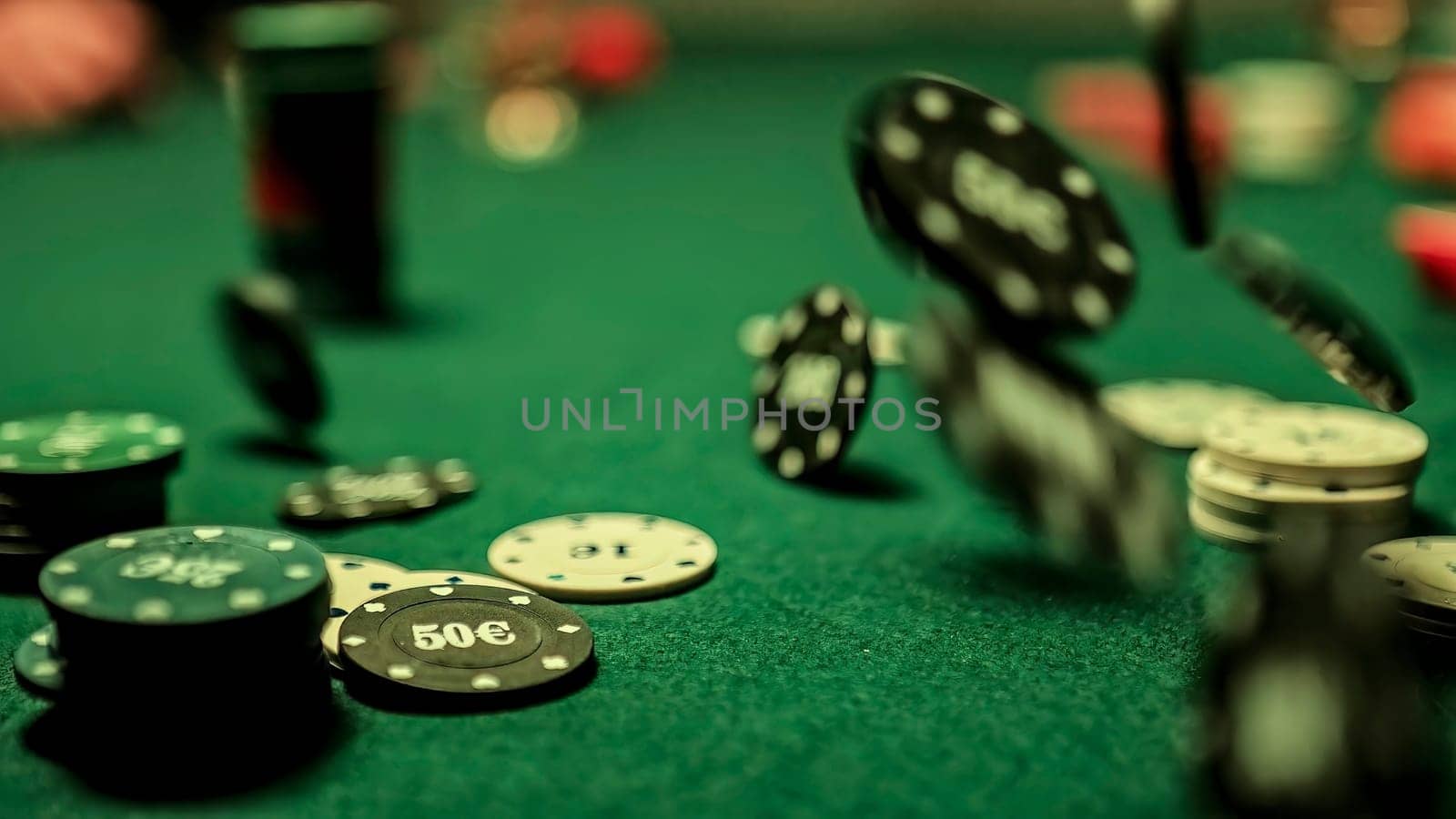 Poker chips falling onto a green felt table during a game, creating a dynamic and exciting atmosphere