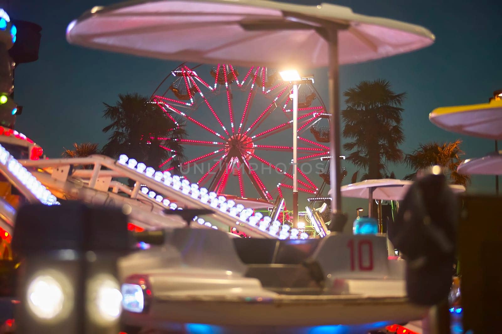 Glowing ferris wheel and colorful amusement park rides light up the night sky