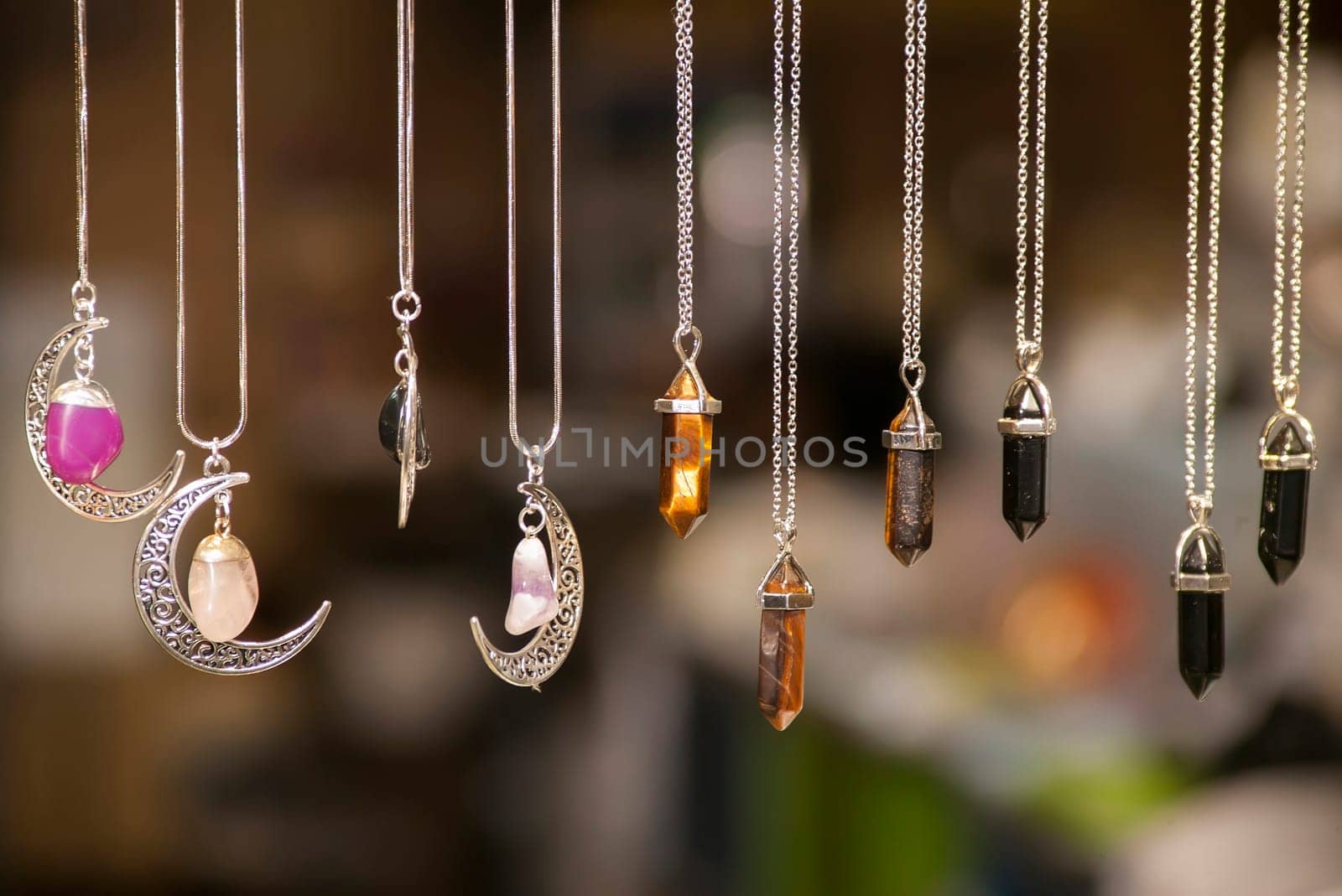 Beautiful handcrafted silver pendants with colorful gemstones hanging on delicate chains, creating a captivating display
