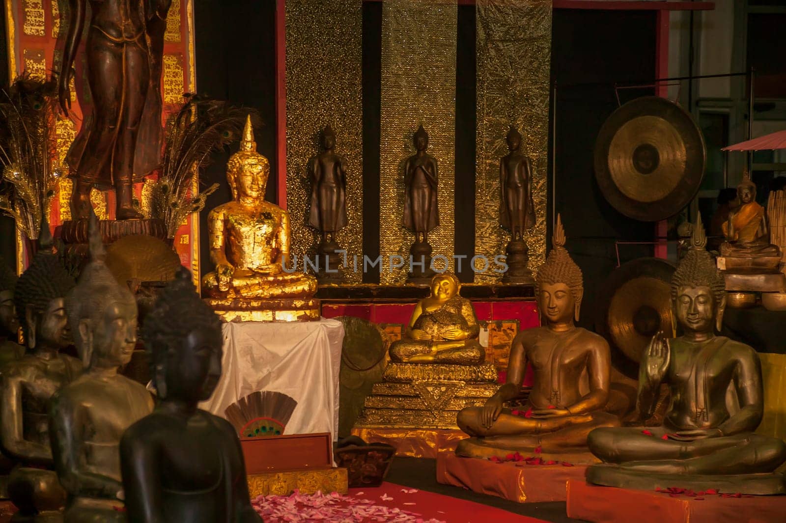 Several buddha statues, crafted from gold and other materials, are displayed within a thai temple, creating a serene and spiritual atmosphere