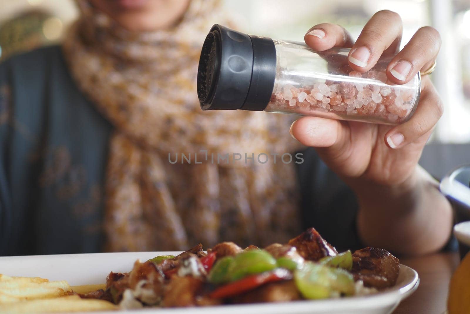 A hand expertly adding a pinch of pink salt to a delicious meal at a lovely restaurant