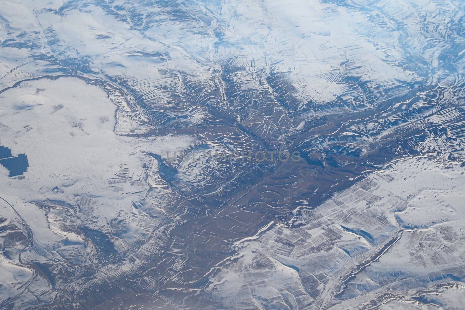 A stunning aerial image shows breathtaking snowy mountains and valleys under clear skies