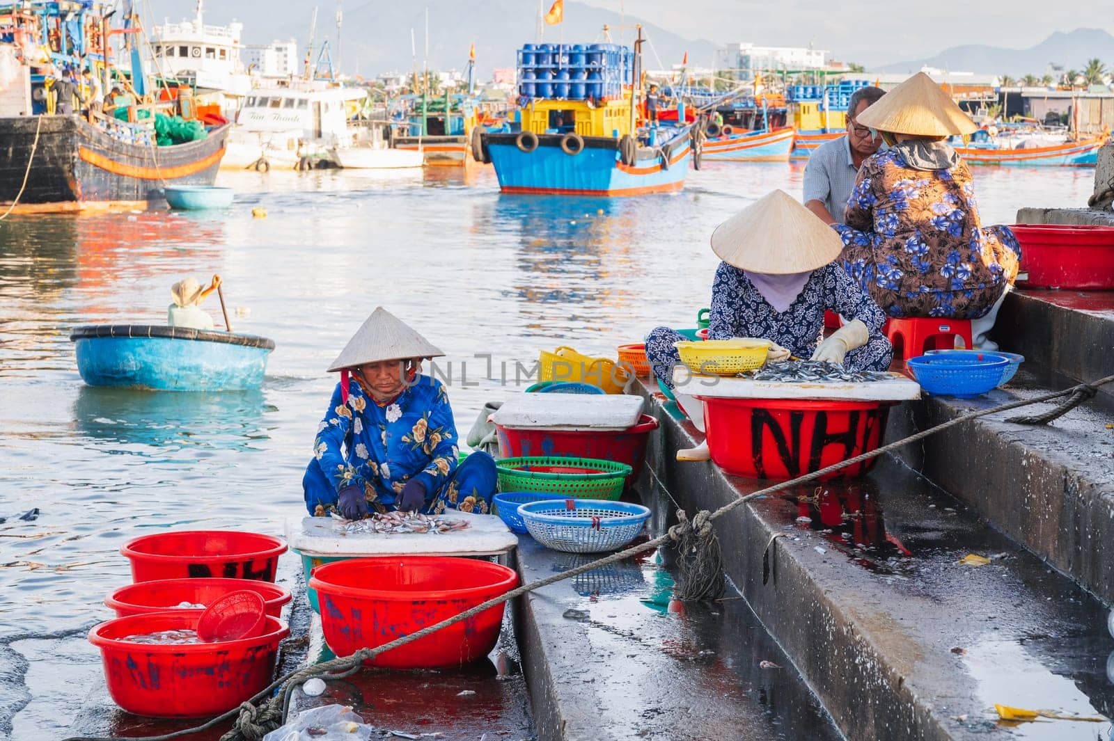 Vietnamese women sit on the steps of the seaport and sell fresh fish. Vietnam, Nha Trang - September 8, 2024