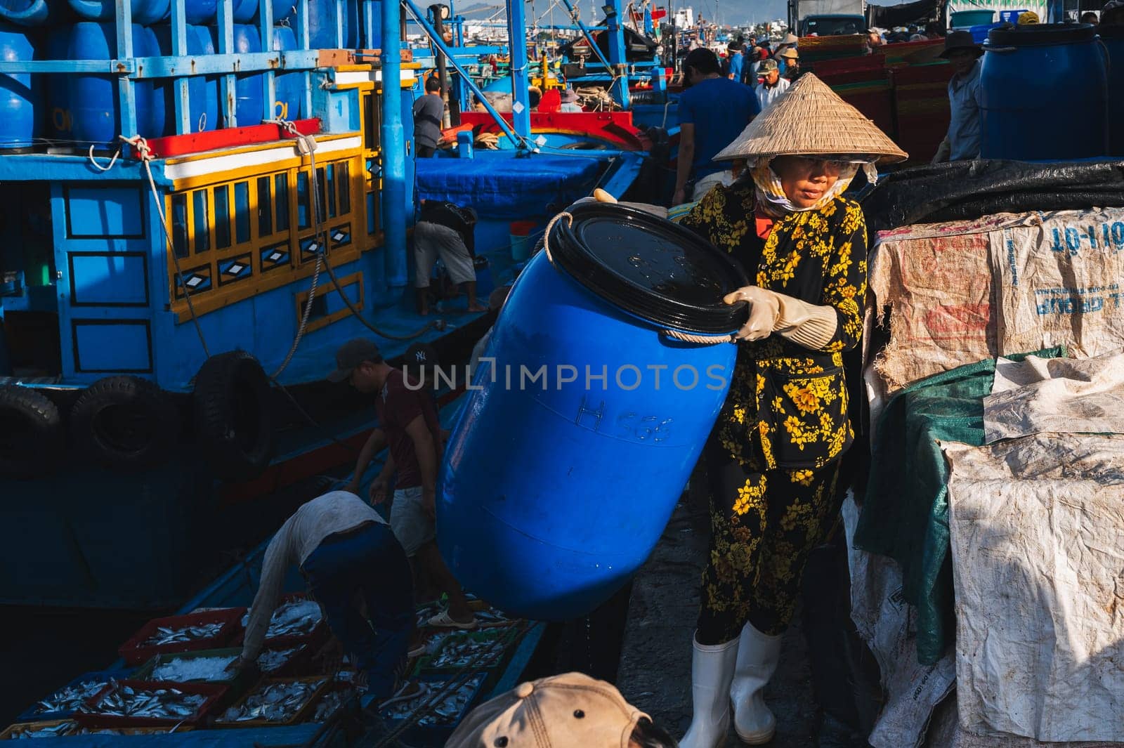 A Vietnamese woman unloads fresh fish for sale at a fish market. Vietnam, Nha Trang - September 8, 2024