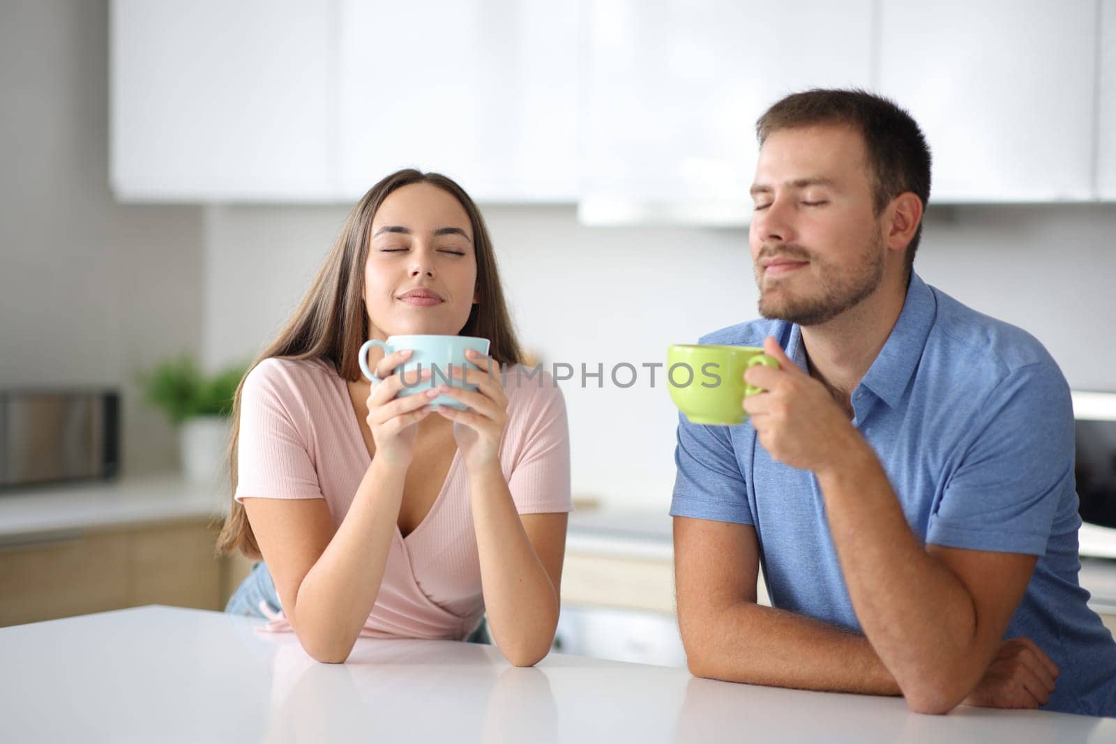 Happy couple smelling coffee or tea in the kitchen at home