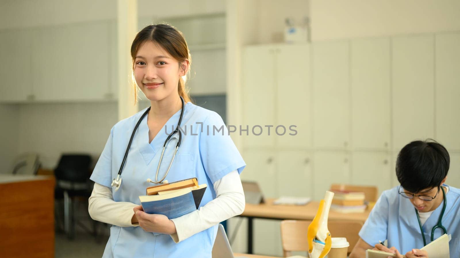 Medical student holding textbooks and smiling confidently at camera.