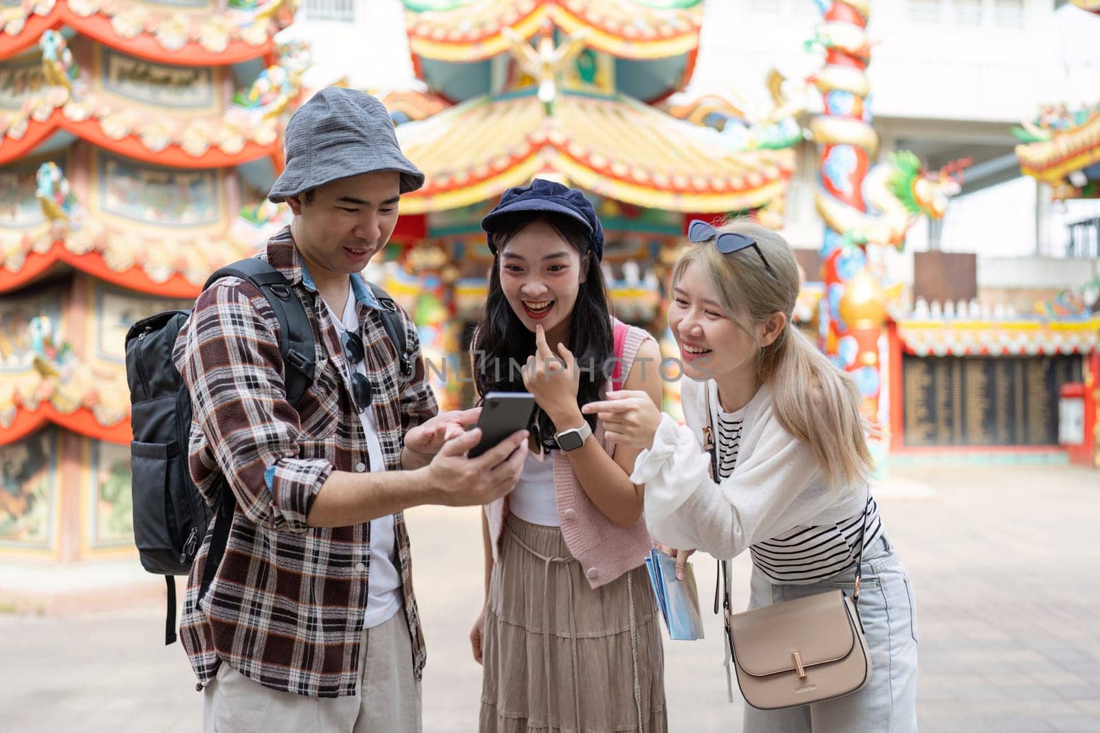 Three friends explore their travel destination sharing laughs and discovering something exciting on their phones.