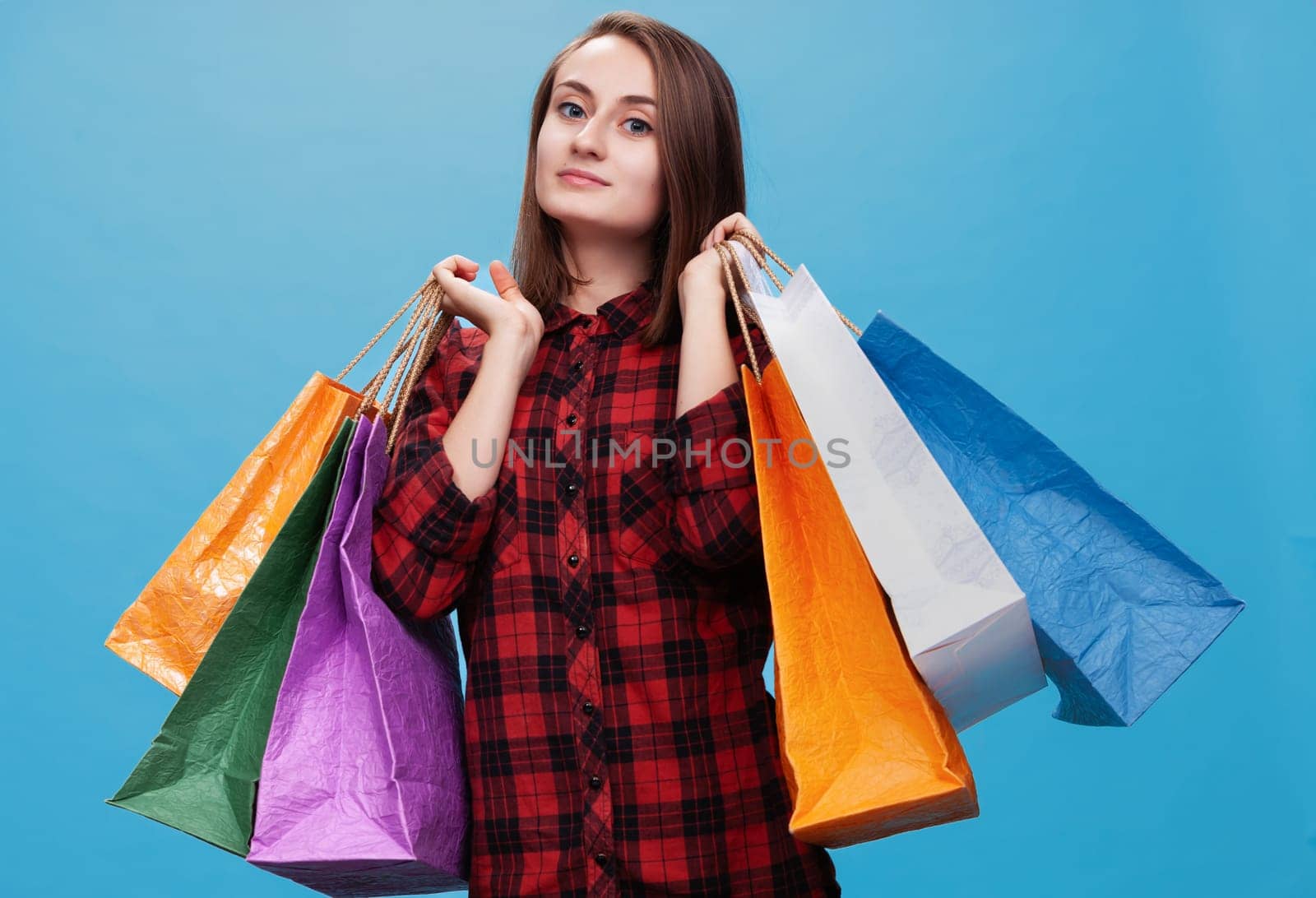 A happy young woman poses confidently with multiple colorful shopping bags.