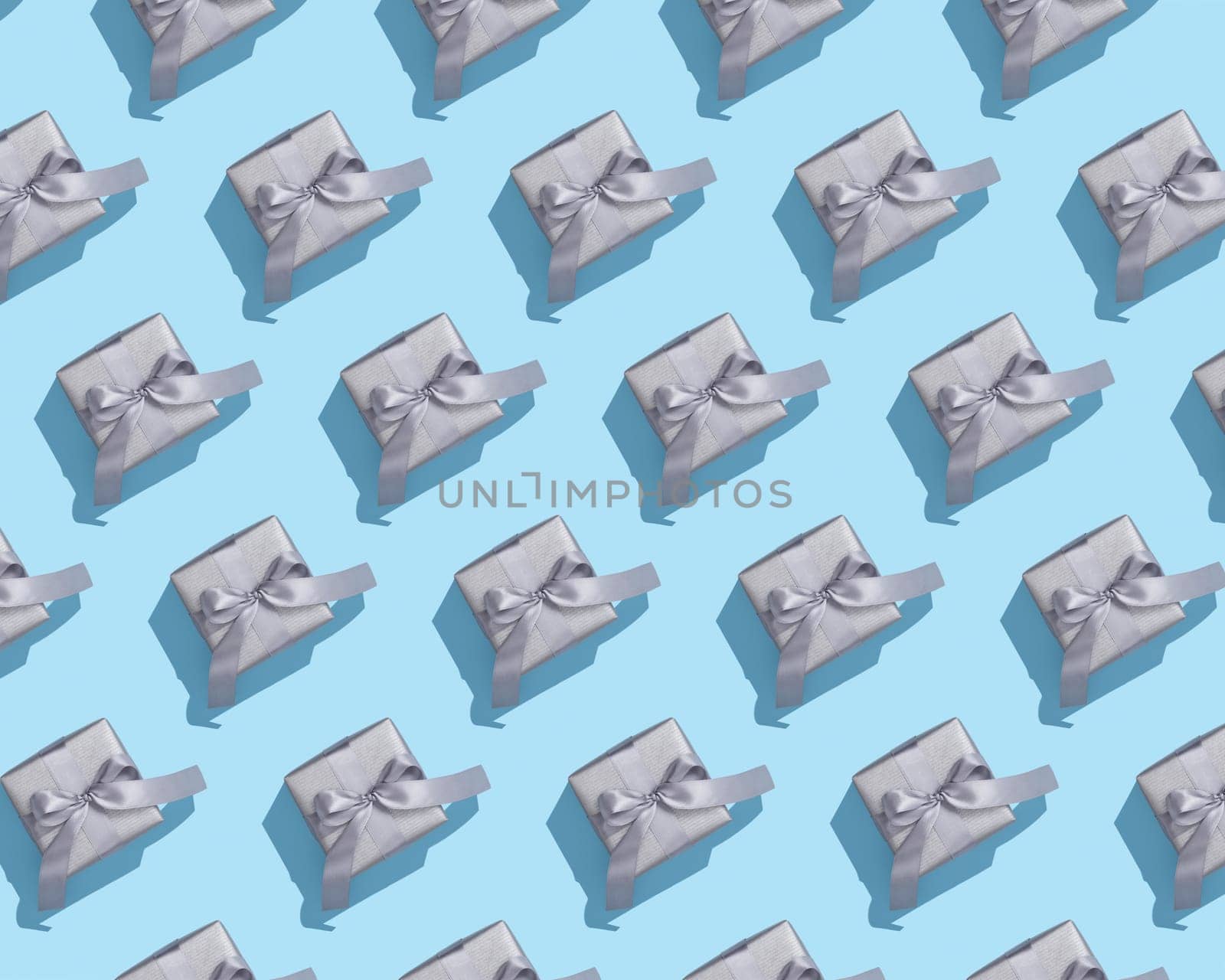 Pattern of silver gift boxes on with gray bows on blue background