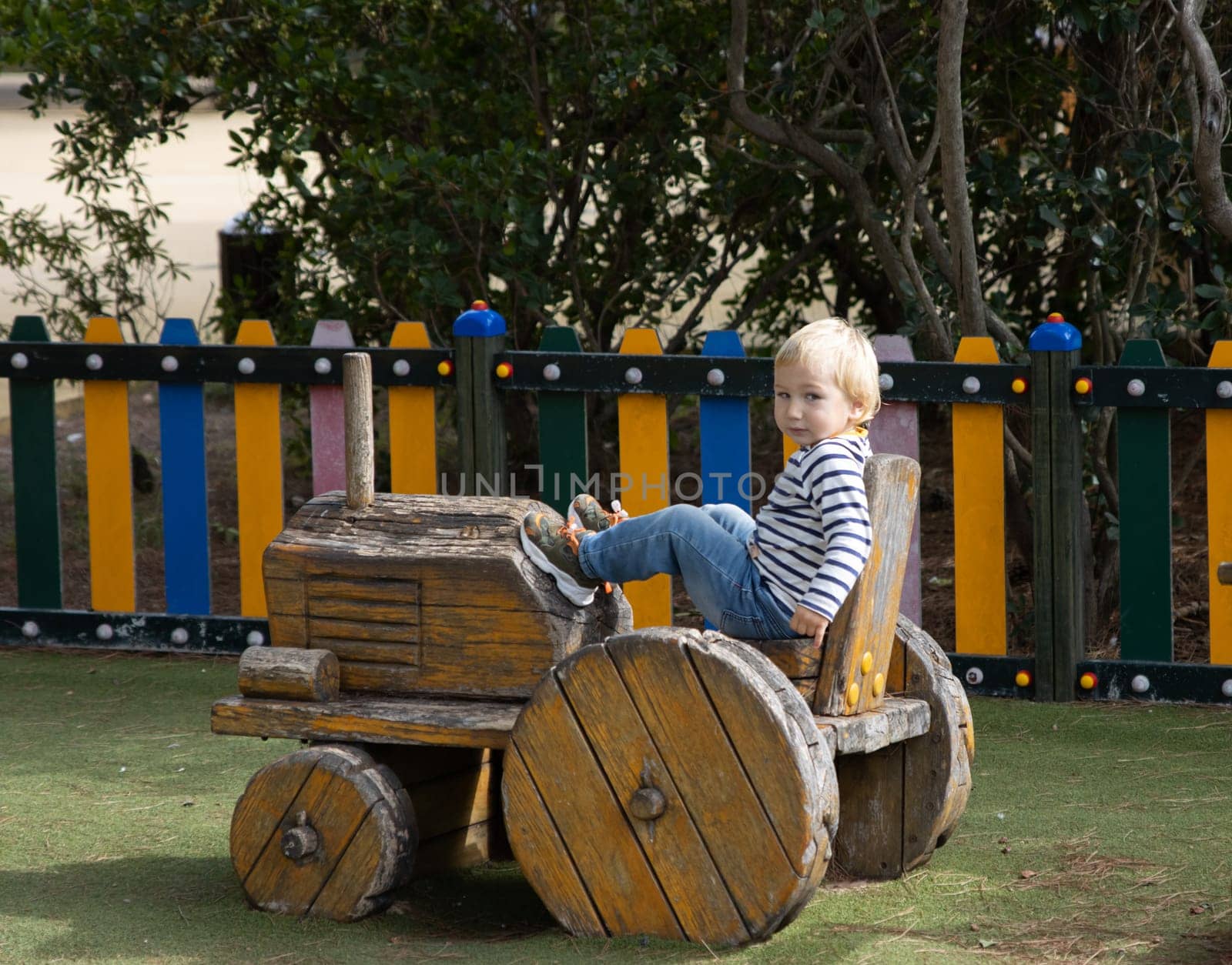 Little boy sitting in a wooden toy tractor on the playground by Studia72