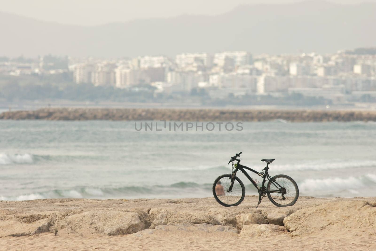 Abandoned bicycle stands on rocks by the sea. Mid shot
