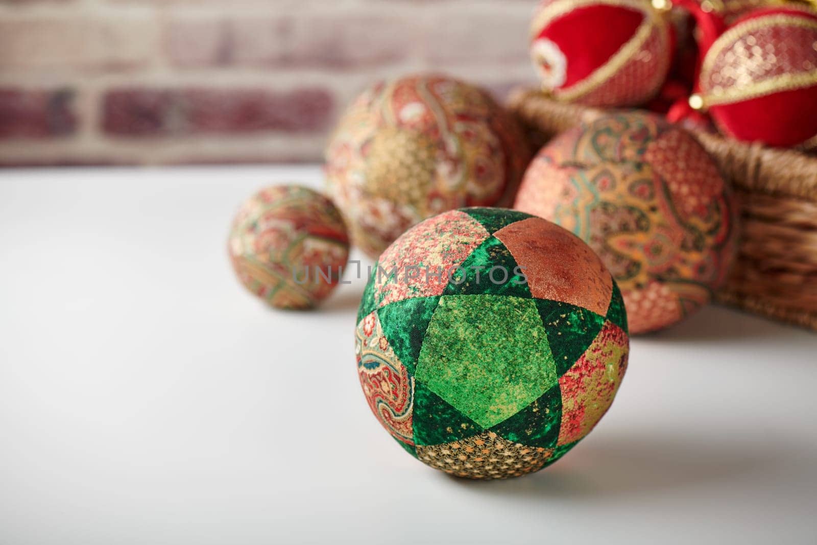 Patchwork puzzle balls and christmas decorations in basket on brick wall background by maxcab