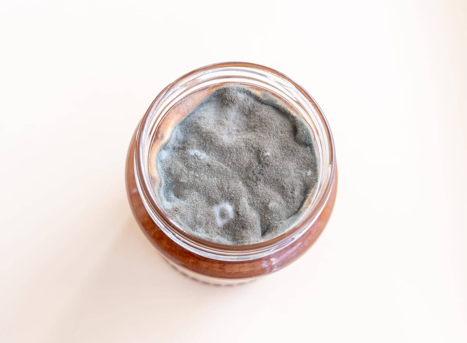 Open jar with sweet jam and mold on a white background. Mold in a jar of raspberry jam. Hazardous to health.