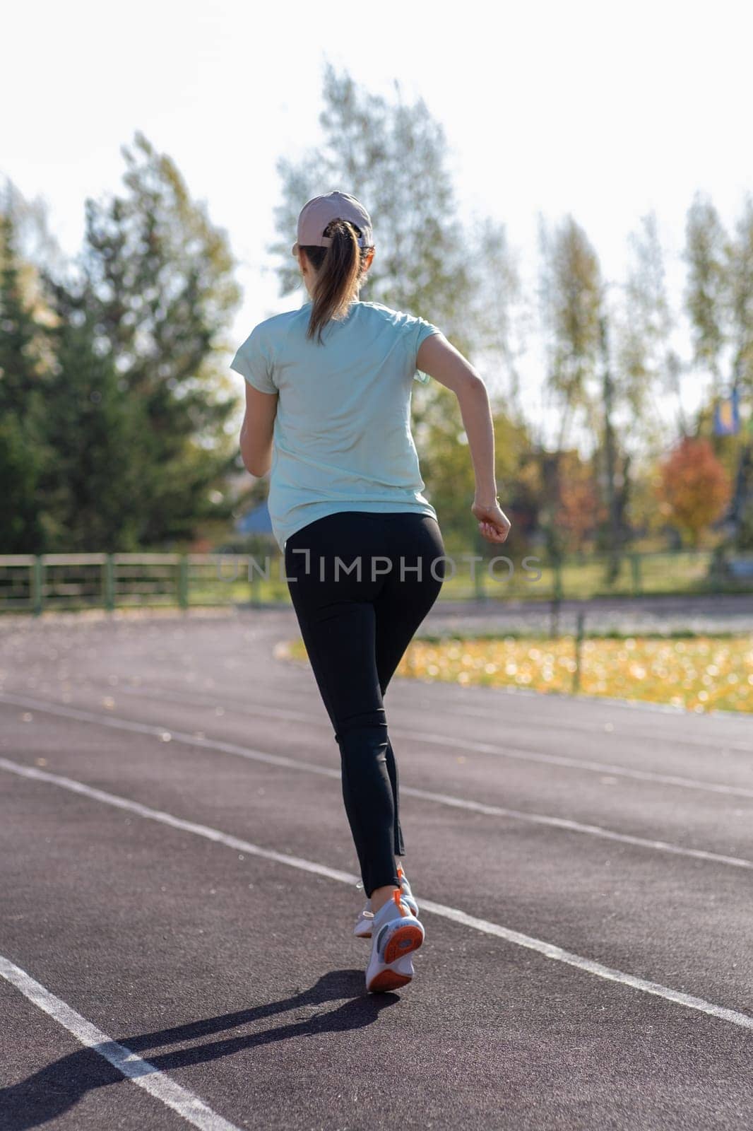 A young beautiful woman in sportswear plays sports at a local stadium. Exercise, jog and exercise at the beginning of the day. Healthy and active lifestyle.