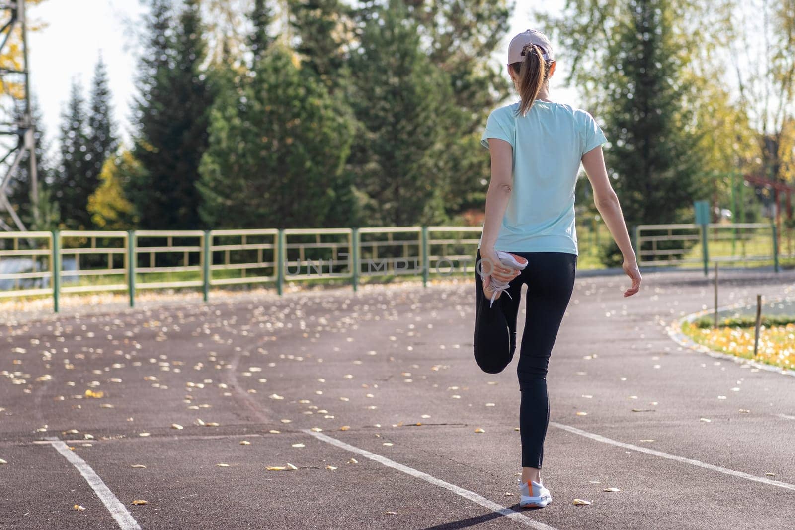 A young beautiful woman in sportswear plays sports at a local stadium by AnatoliiFoto