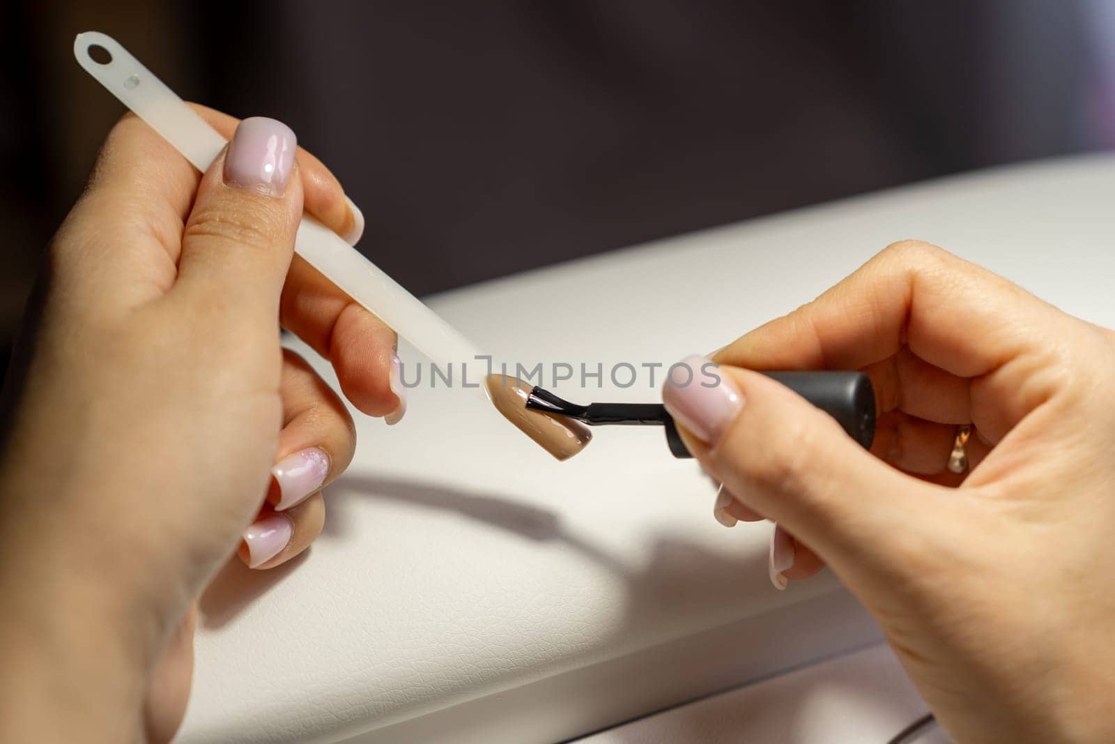 A manicurist applies gel nail polish to empty tips as a sample for future clients. Large range of gel polishes. Spa body care concept. Nail technician