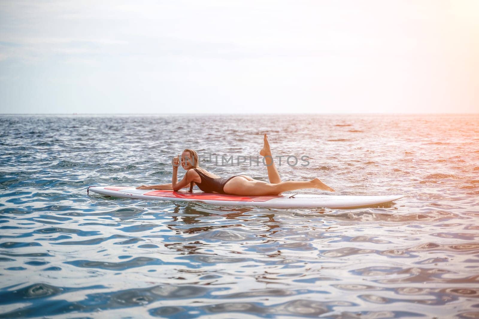 Woman sup sea. Sports girl on a surfboard in the sea on a sunny summer day. In a black bathing suit, he sits on a sapa in the sea. Rest on the sea. by Matiunina