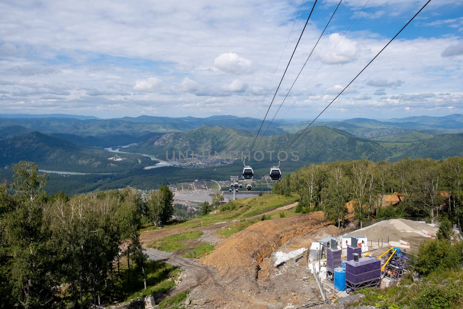 View from the mountain of the cable car with cabins. There is construction going on underneath them. Cable car trip to viewpoints in mountains. Tourists enjoy beautiful views and experience exciting.