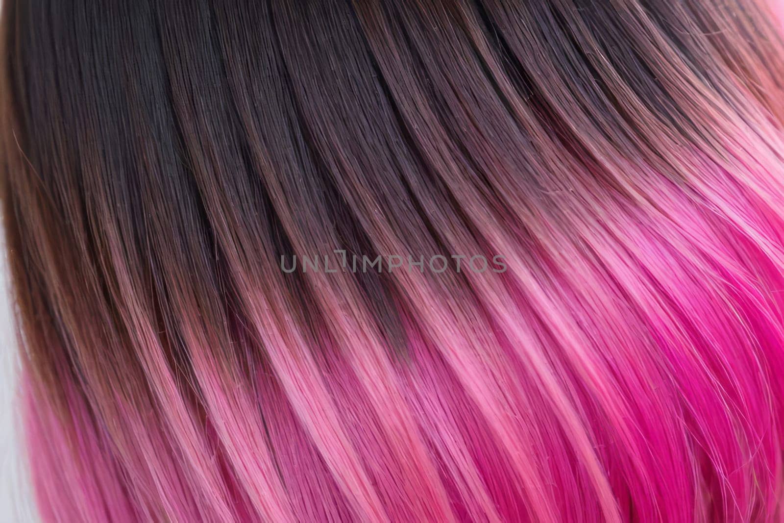 This close-up photo accentuates the vibrant allure of pink hair in an ombre design, revealing a harmonious fusion of colors and textures