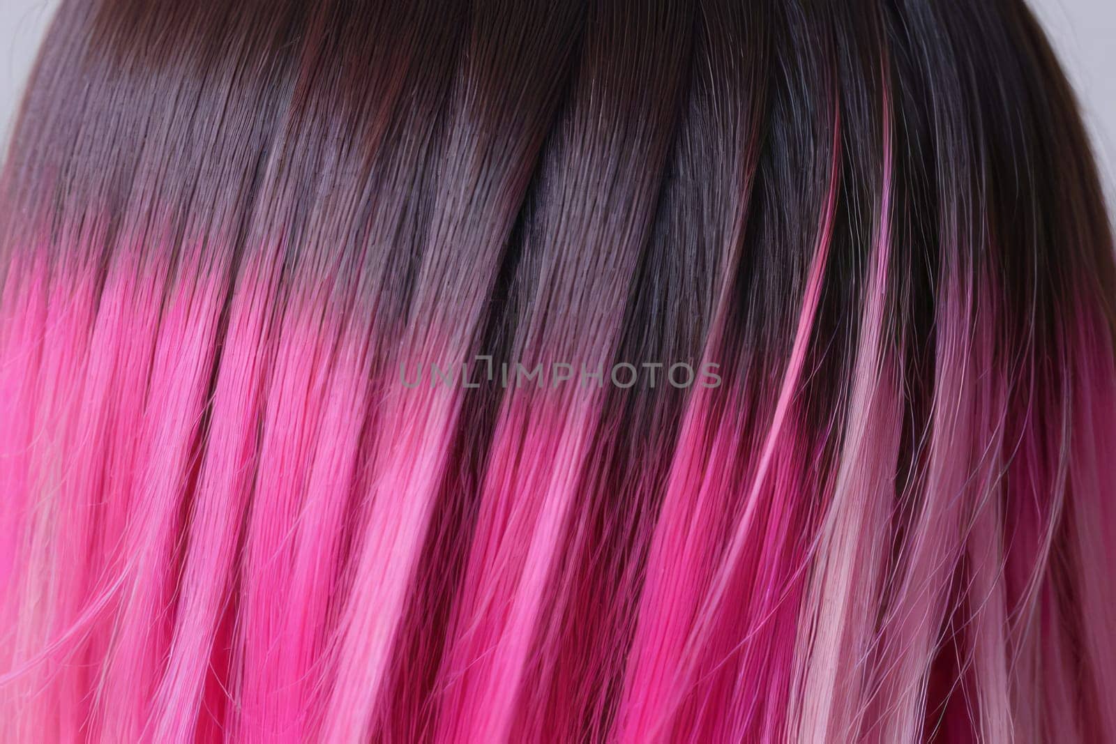 This close-up photo accentuates the vibrant allure of pink hair in an ombre design, revealing a harmonious fusion of colors and textures