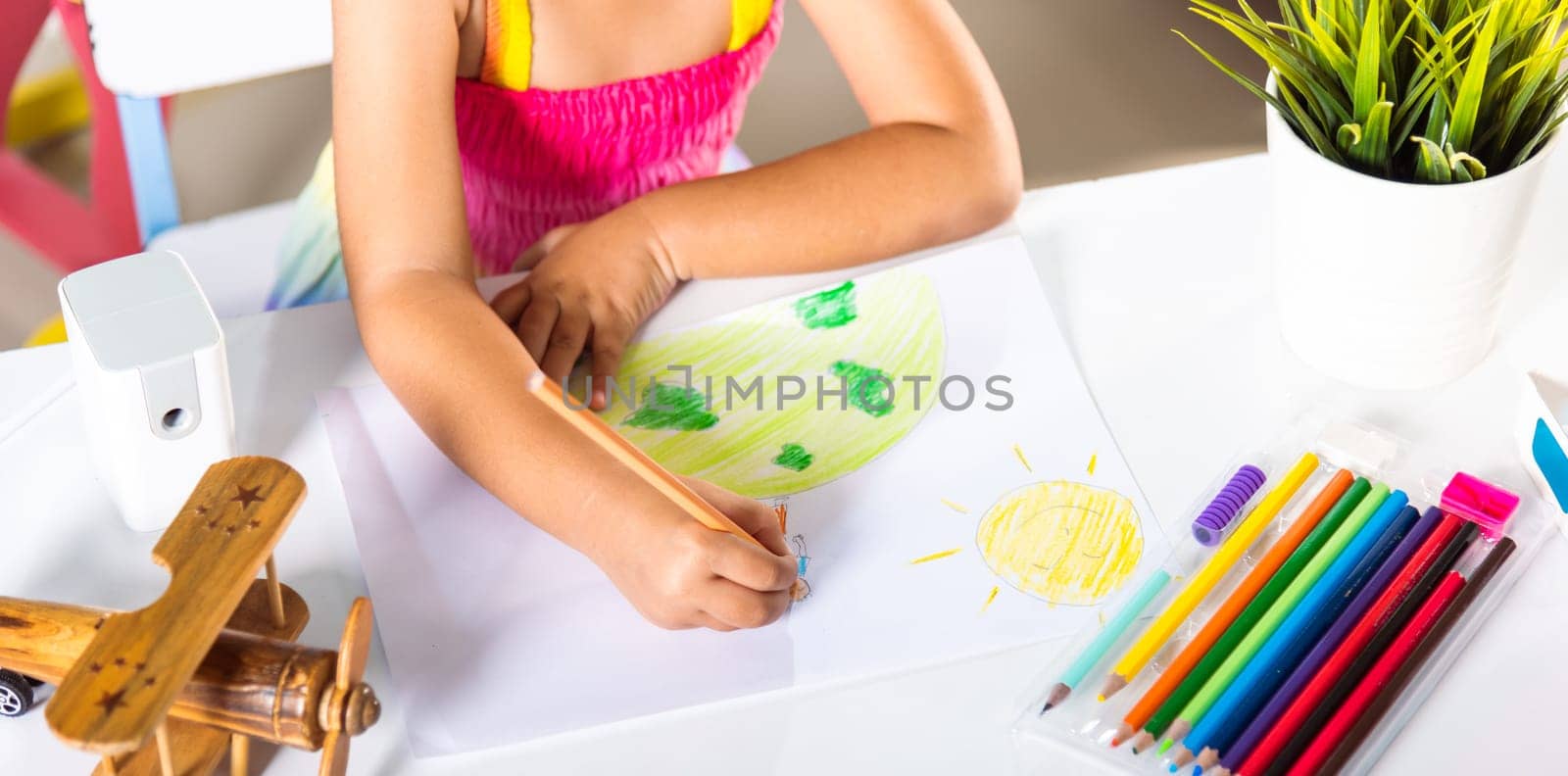 Asian cute kid preschooler sit on table smiling she draw picture with pencil at home, Happy child little girl colorful drawing family standing hold hands on planet earth on paper, earth day concept