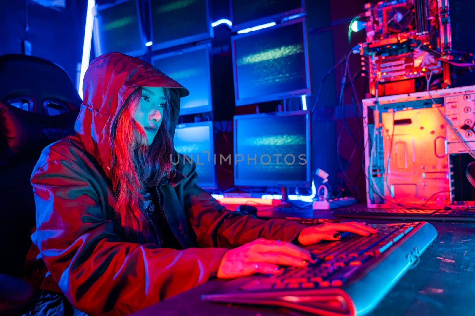 Woman hacker. Asian woman wearing hood is typing keyboard for coding hacking programming system. room is dimly lit. possibly typing or browsing internet, Hacker in neon light, Female gamer play game