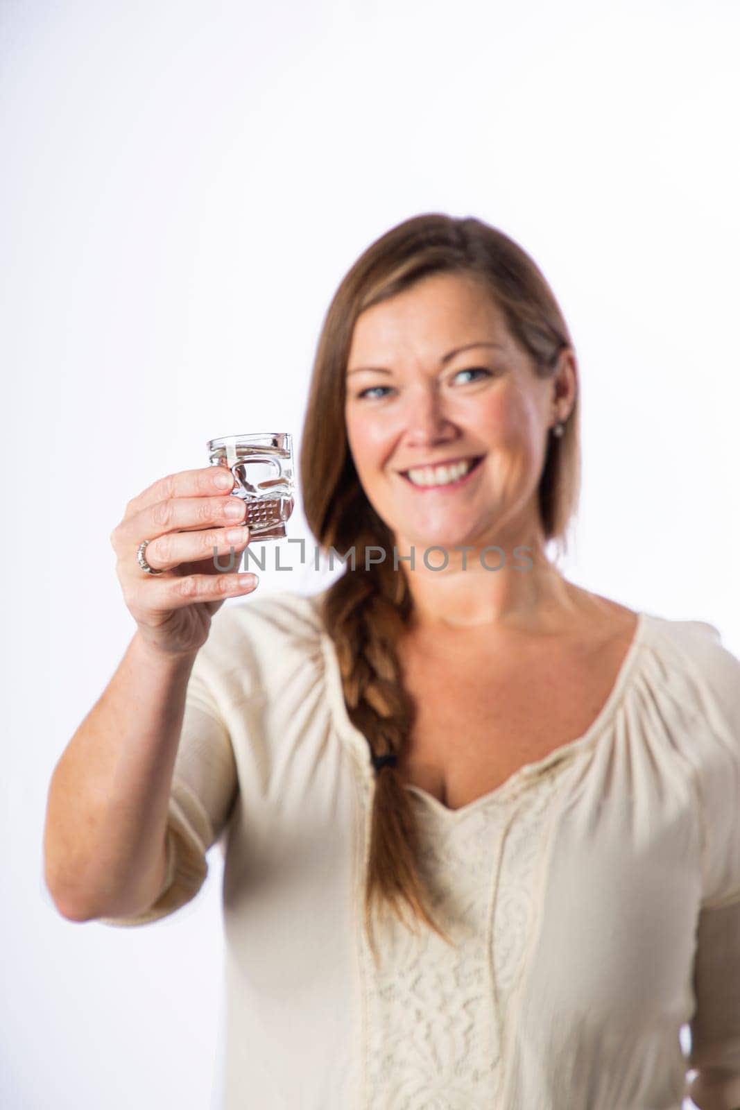Forty something woman, wearing casual clothes, offering a shot of alcohol, from a skull shooter glass