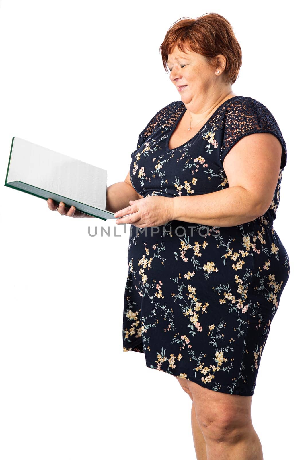 Fifty something woman holding a large green book laughing at the content