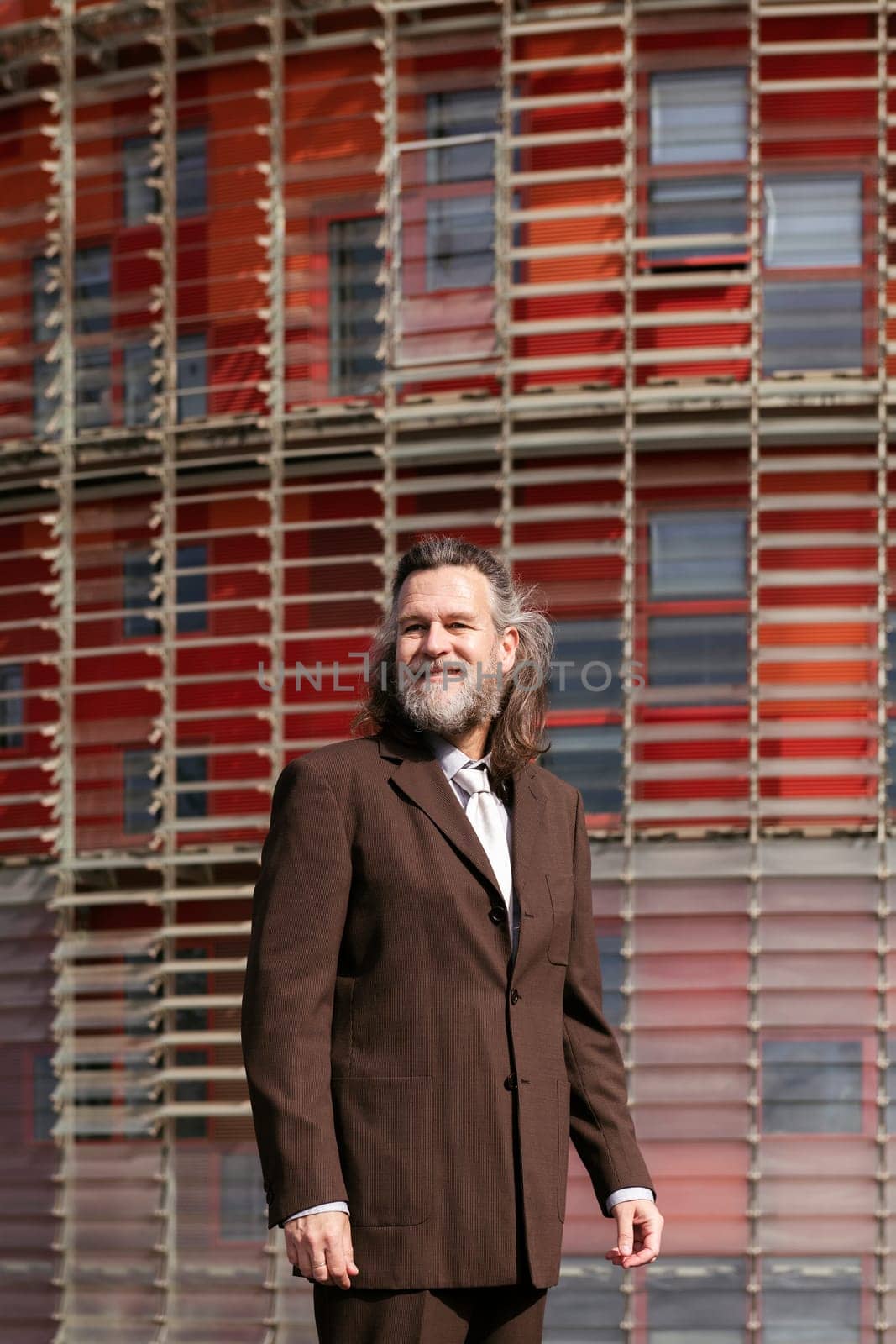 positive middle age male with beard in elegant suit standing looking away pensive against urban building, concept of business and mature man lifestyle, copyspace for text
