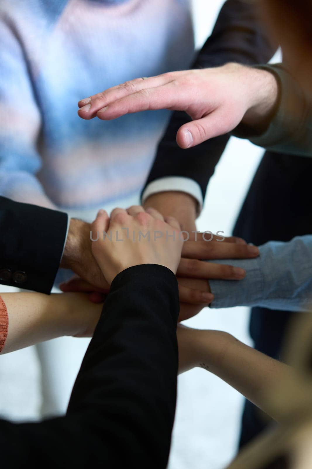 A top view of business people joining hands in a circle, symbolizing unity, collaboration, and shared success in the workplace.