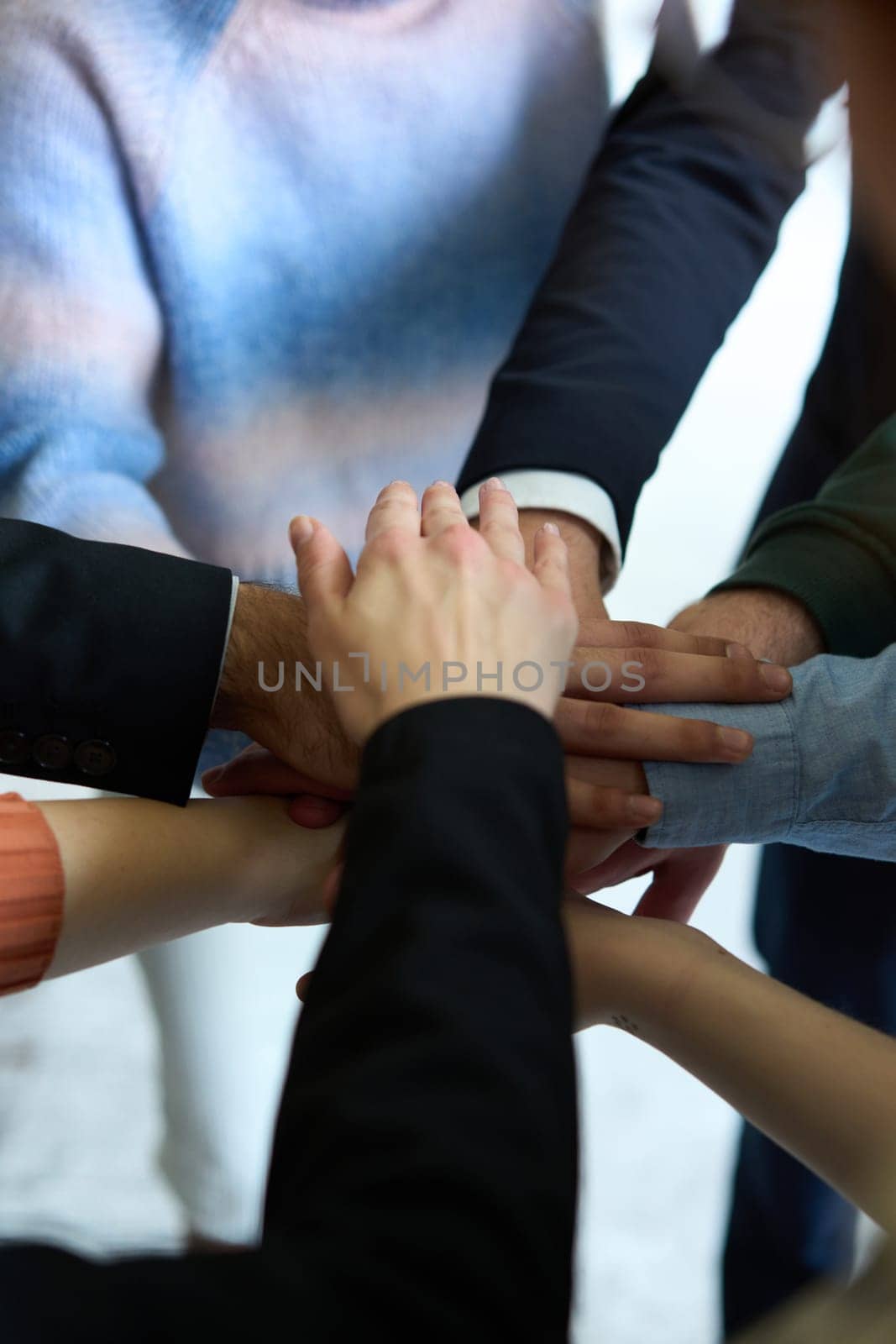 A top view of business people joining hands in a circle, symbolizing unity, collaboration, and shared success in the workplace.