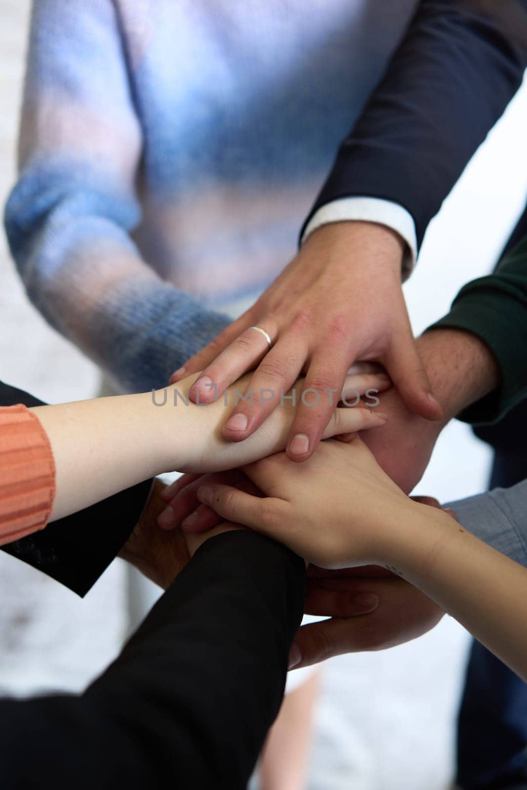 A top view of business people joining hands in a circle, symbolizing unity, collaboration, and shared success in the workplace.