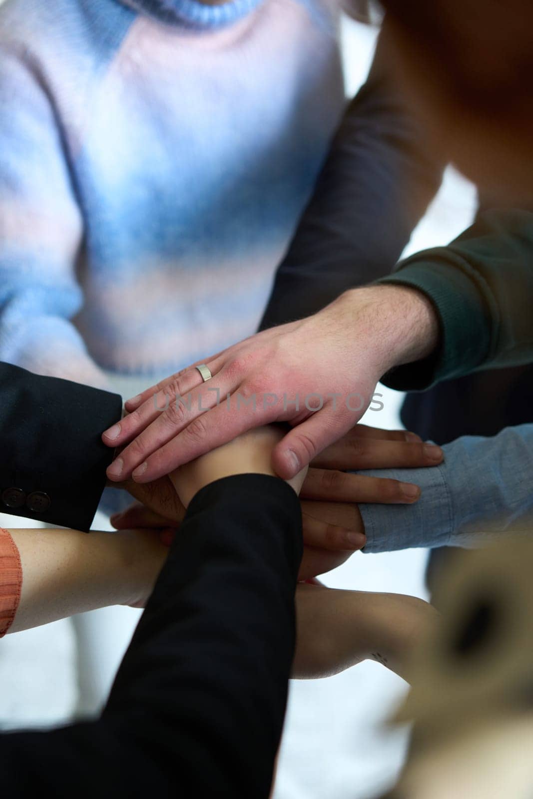 A top view of business people joining hands in a circle, symbolizing unity, collaboration, and shared success in the workplace.