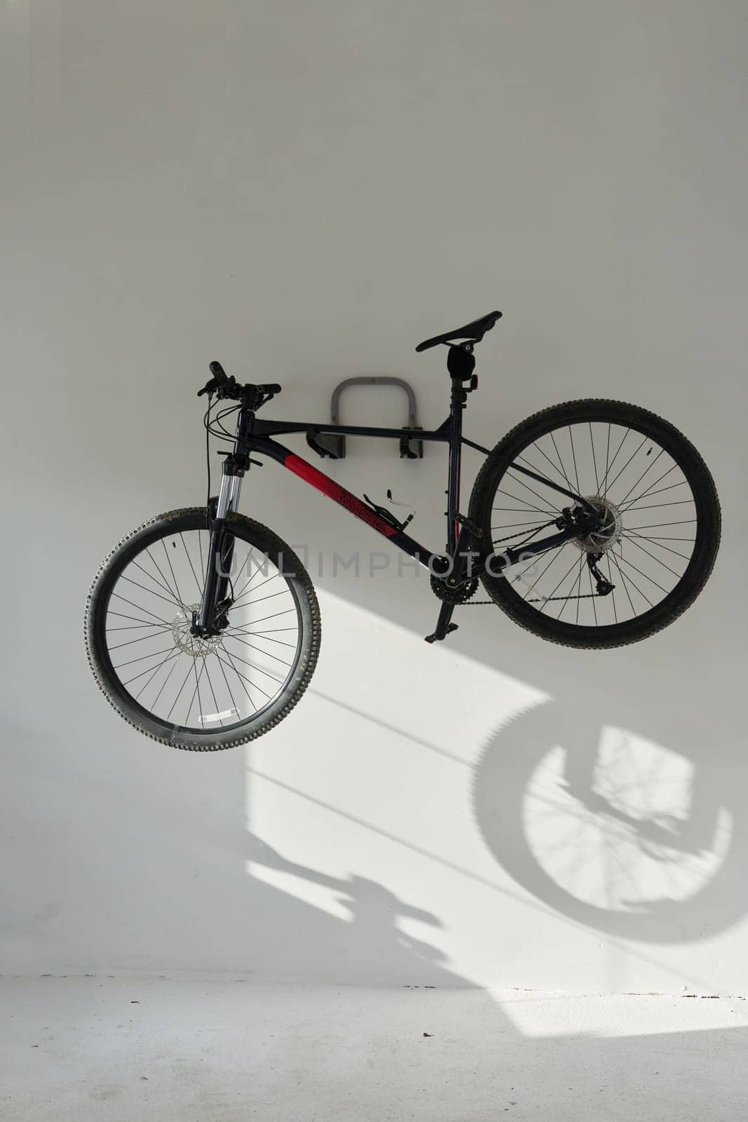 A mountain bike hanging on a white wall in garrage.