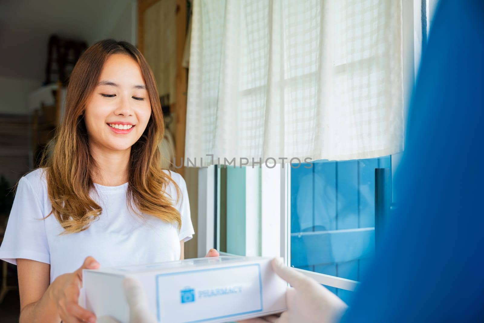 Sick Asian young woman receive medication first aid pharmacy box from hospital delivery service, delivery man give medicine drug to patient female at home, healthcare medicine online concept