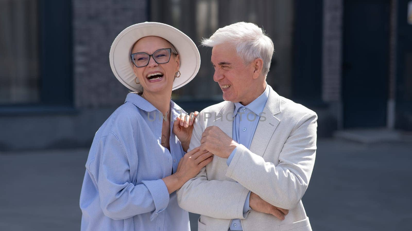 An elderly couple in love walks through the city. Portrait of a stylish gray-haired man and woman. by mrwed54