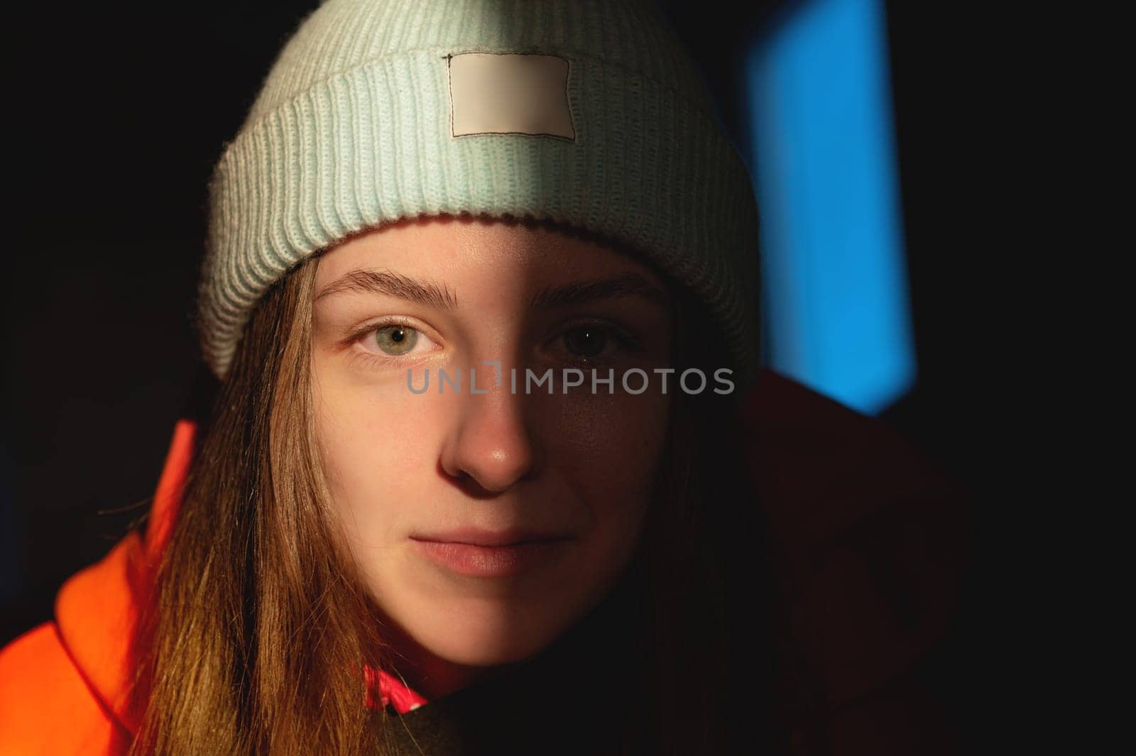 cute girl in a hat, warm portrait. the sunset rays of the sun fall on her face, covering half of her head.