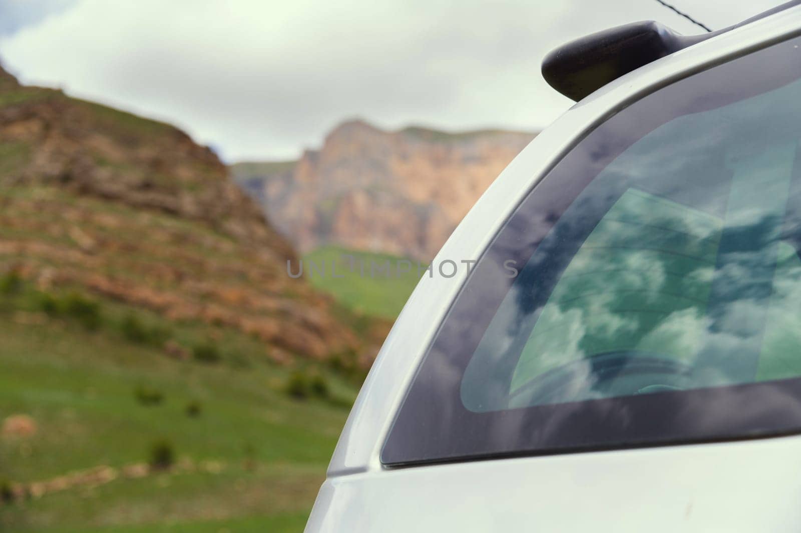 Side of a gray car, beautiful reflection of the sky. Reflections of clouds in a new car, which is parked in the mountains in summer.