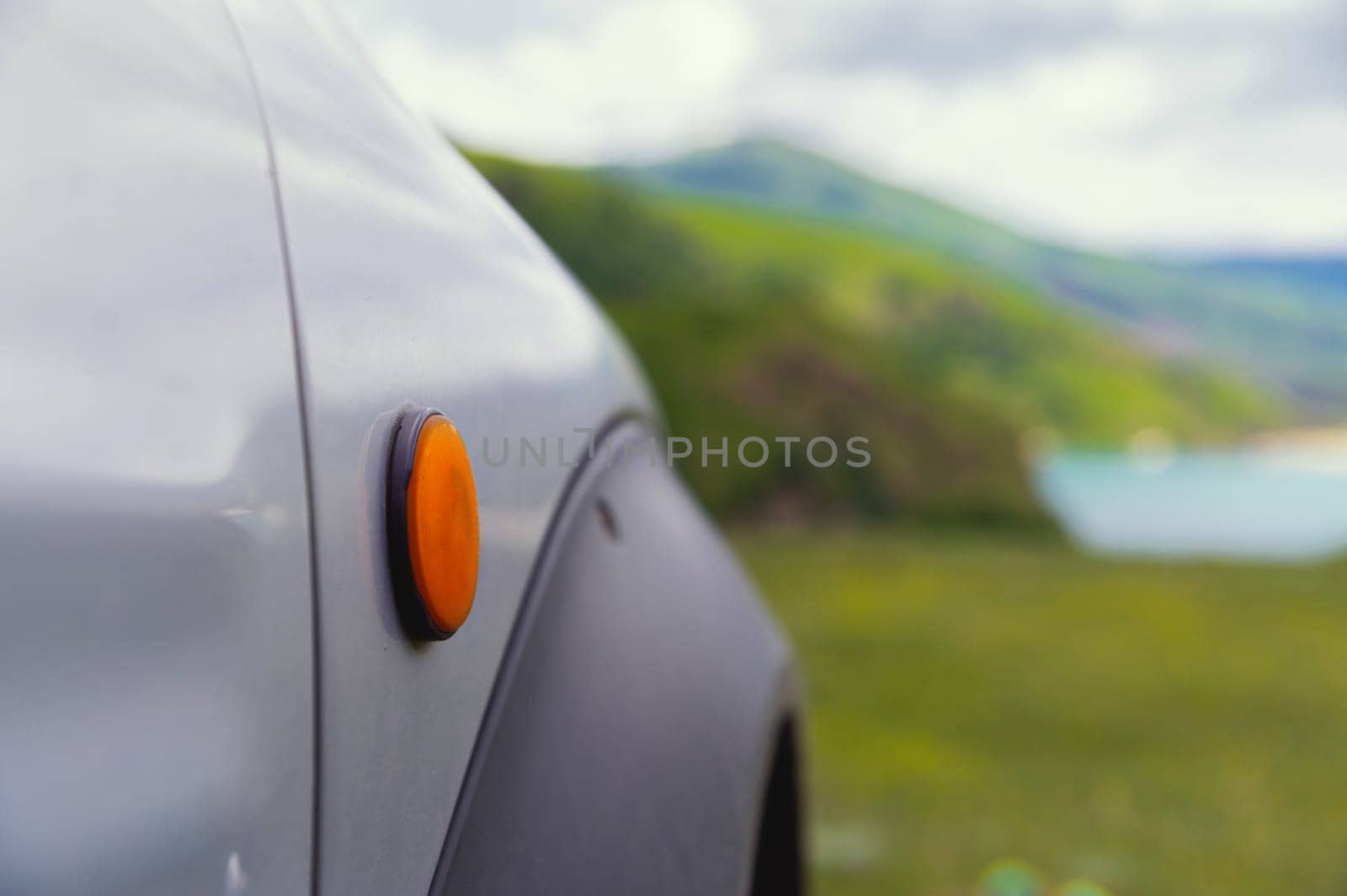 wheel under the fender of an SUV, extreme off-road ride, close-up of the fender of a clean car. green mountains can be seen in the background.