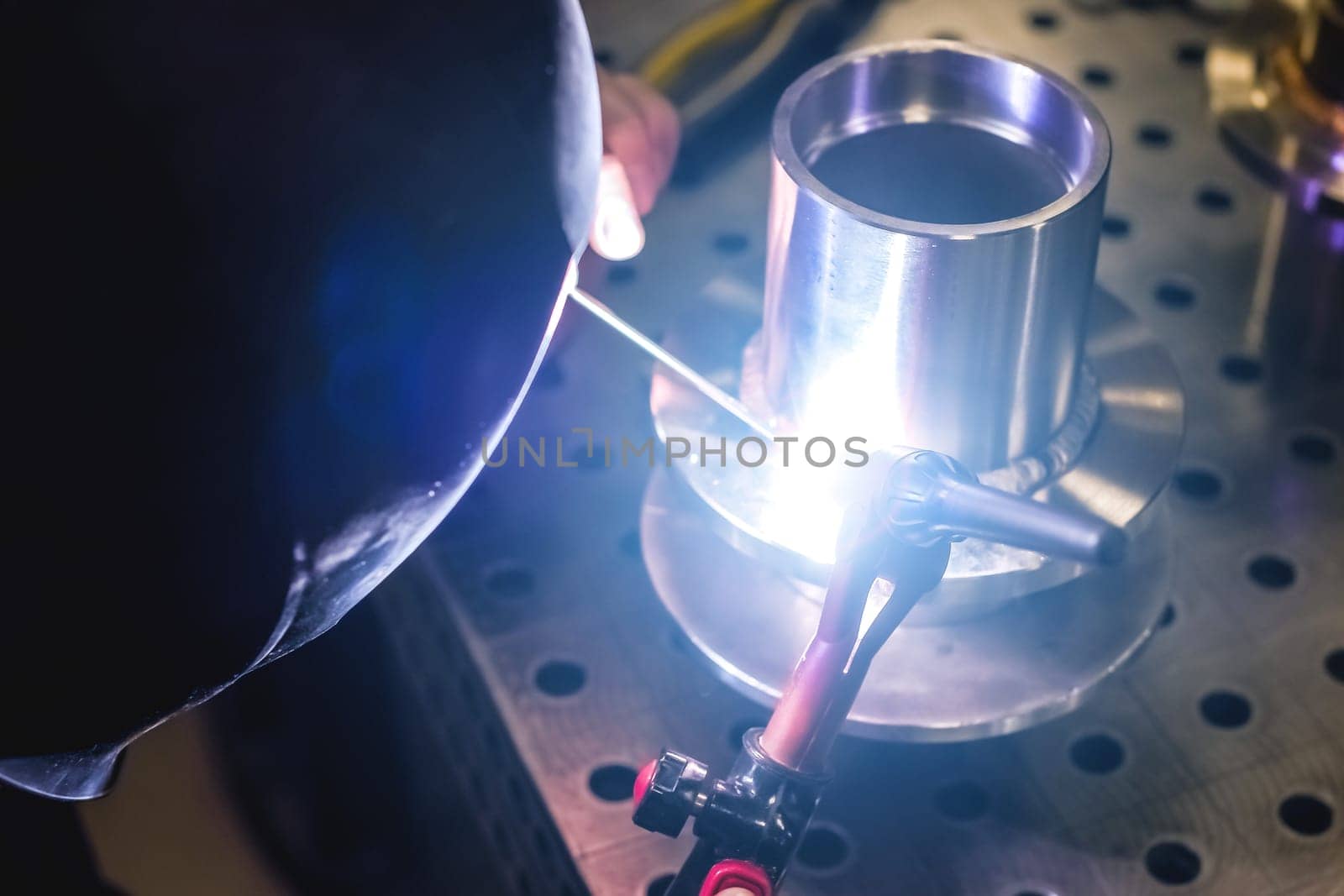 A welder makes a precision weld on a stainless-steel element. The element is used for professional kitchen equipment